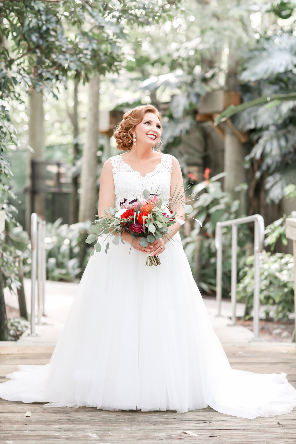 Outdoor Florida Bride Wedding Portrait in V Neckline Tank Top Strap Lace and Illusion Bodice and Ballgown Skirt Wedding Dress with Tropical Inspired, Red, Orange, and Greenery Floral Bouquet | Tampa Bay Wedding Photographer Lifelong Photography Studio | Hair and Makeup Michele Renee the Studio