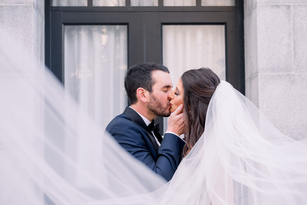 Creative Bride and Groom Kissing Wedding Portrait with Veil Blowing in the Wind | Tampa Bay Wedding Planner Breezin Entertainment