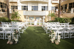 Outdoor Lawn Wedding Ceremony, White Folding Chairs, Ivory, Purple and Greenery Flower Decor, White Tall and Small Lanterns, White Pedestals with Floral Bouquets | Tampa Bay Wedding Photographer Lifelong Photography Studios | Clearwater Beach Wedding Hotel Venue Sandpearl Resort | Wedding Planner Special Events Planning