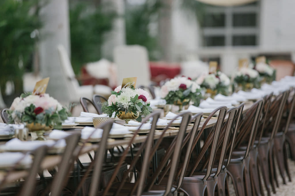 Open Air St. Pete Wedding Reception with Farm Tables and Metal Chairs with Vintage Tabletop Decor Accents in Gold Cauldron with Ivory and Pink Florals and Greenery | Outdoor St. Pete Wedding Reception Venue Intermezzo