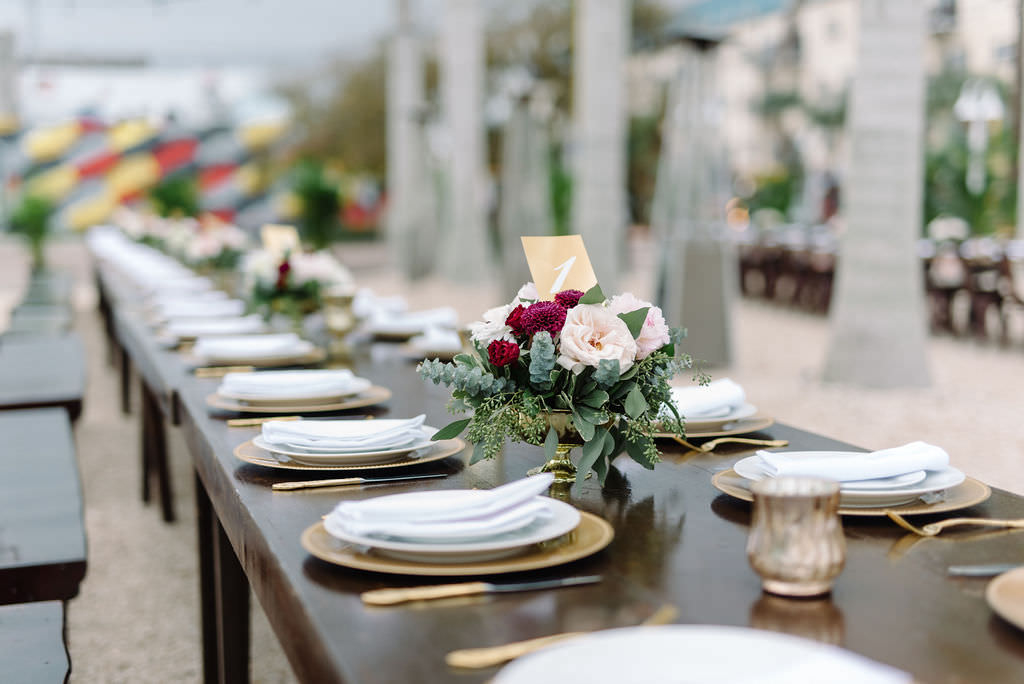 Open Air St. Pete Wedding Reception with Farm Tables and Metal Chairs with Vintage Tabletop Decor Accents in Gold Cauldron with Ivory and Pink Florals and Greenery | Outdoor St. Pete Wedding Reception Venue Intermezzo