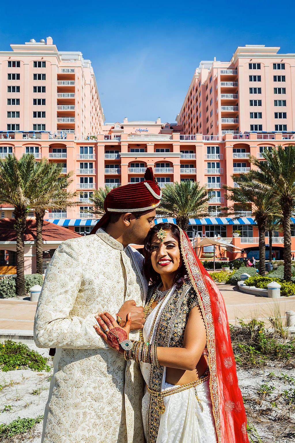Florida Indian Hindu Bride and Groom Wedding Portrait, Bride in White and Gold Sari with Red and Gold Dupatta Veil, Groom in Traditional Sherwani and Red Turban | Clearwater Beach Wedding Waterfront Venue Hyatt Regency Clearwater | Hair and Makeup Destiny and Light Hair and Makeup Group