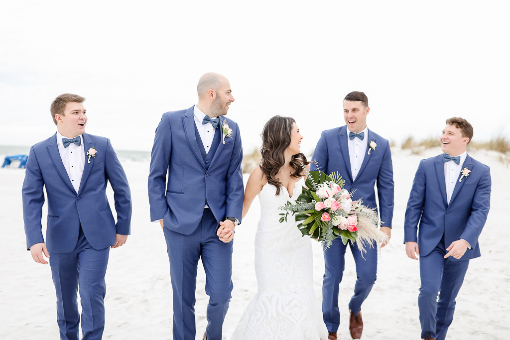 Bride and Groom with Groomsmen Wedding Beach Portrait, Groomsmen in Blue Tuxedo with Bowtie, Spaghetti Strap Sweetheart Neckline White Fitted Hayley Paige Wedding Dress, Carrying White and Pink Flower Bouquet with Green Palms | Photographer Lifelong Photography Studios