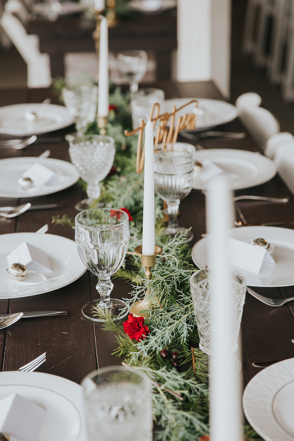 Romantic Christmas Inspired Wedding Decor Centerpieces with Wooden Farm Table, Crystal Goblets, Gold Candelabra, White Candlesticks, Garland Greenery with Red Florals