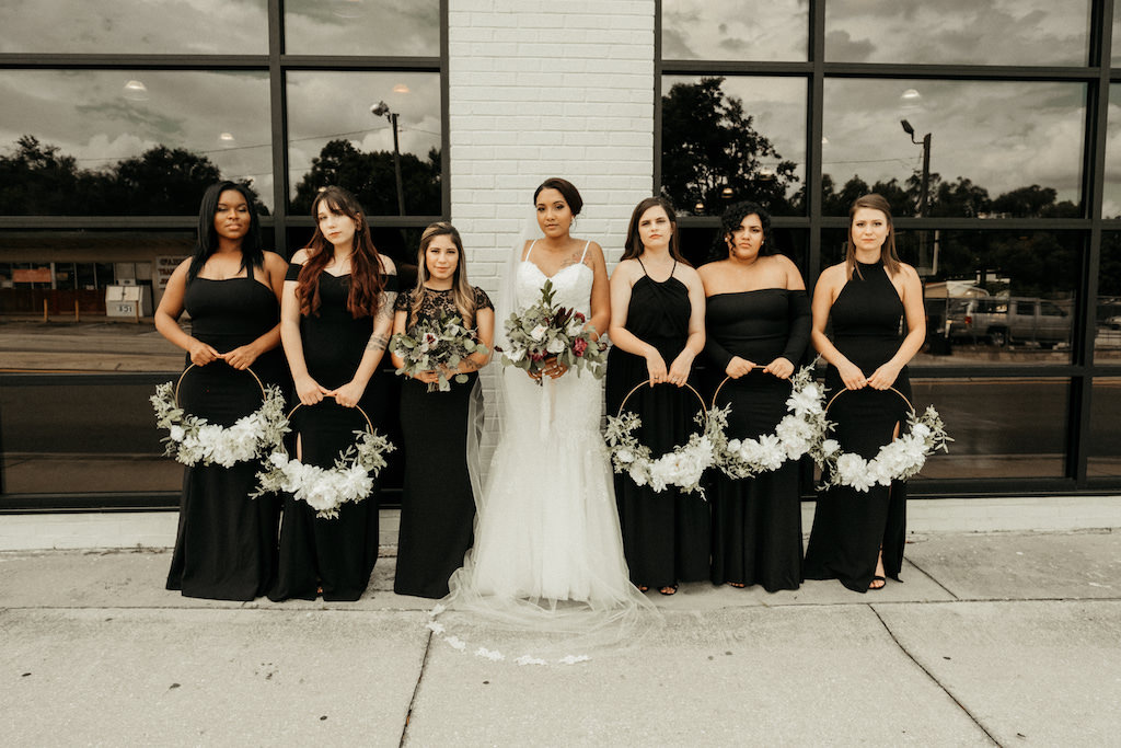Tampa Bay Bride and Bridesmaids Wedding Portrait, Bridesmaids in Mismatched Black Dresses with Circular White and Greenery Floral Bouquets, Bride in Spaghetti Strap Sweetheart Neckline Mermaid and Tulle Skirt Wedding Dress with Dark Colored Greenery and Ivory Floral Bouquet