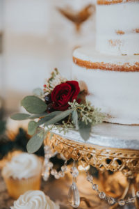 Two Tier Rustic Naked Half-Frosted White Wedding Cake with Rich Red Florals and Greenery, on Gold and Crystal Beaded Cake Stand, Vanilla and Chocolate White Frosted Cupcakes on Gold Tiered Trays, Christmas Inspired Wedding Decor