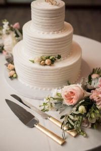 Classic White Three Tier Round Wedding Cake Garnished with Tea Roses and Greenery