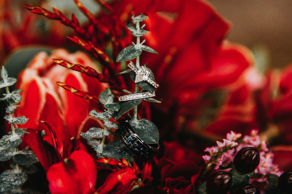 Pear Shaped Diamond Engagement Ring and Wedding Bands against Rich Red Florals and Greenery