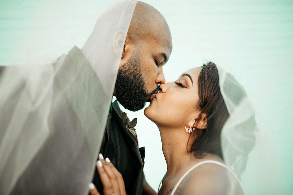 Florida Bride and Groom Intimate Kissing Wedding Portrait with Veil Blowing in Wind