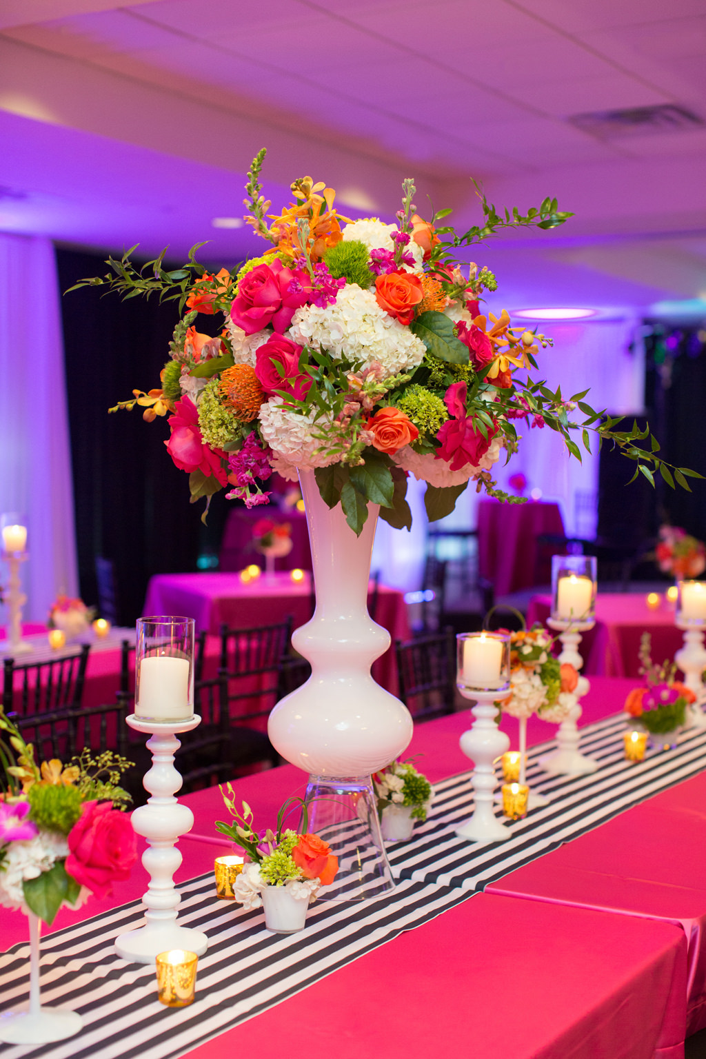 Whimsical Kate Spade Inspired Wedding Reception Decor, Long Table with Hot Pink Tablecloth, Black and White Stripe Table Runner, Tall White Vase with Colorful Pink, Orange, Yellow, White and Green Flower Centerpiece, White Candlesticks | Tampa Bay Wedding Planner Parties A La Carte