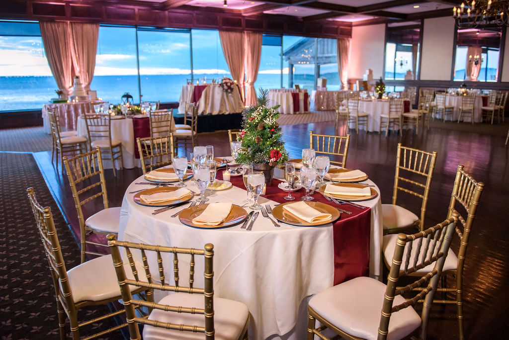 Ballroom Christmas Inspired Wedding Reception Decor, Round Tables with White Tablecloths, Red Table Runner, Gold Chargers, Gold Chiavari Chairs, Christmas Tree Centerpiece | Tampa Bay Wedding Venue Rusty Pelican