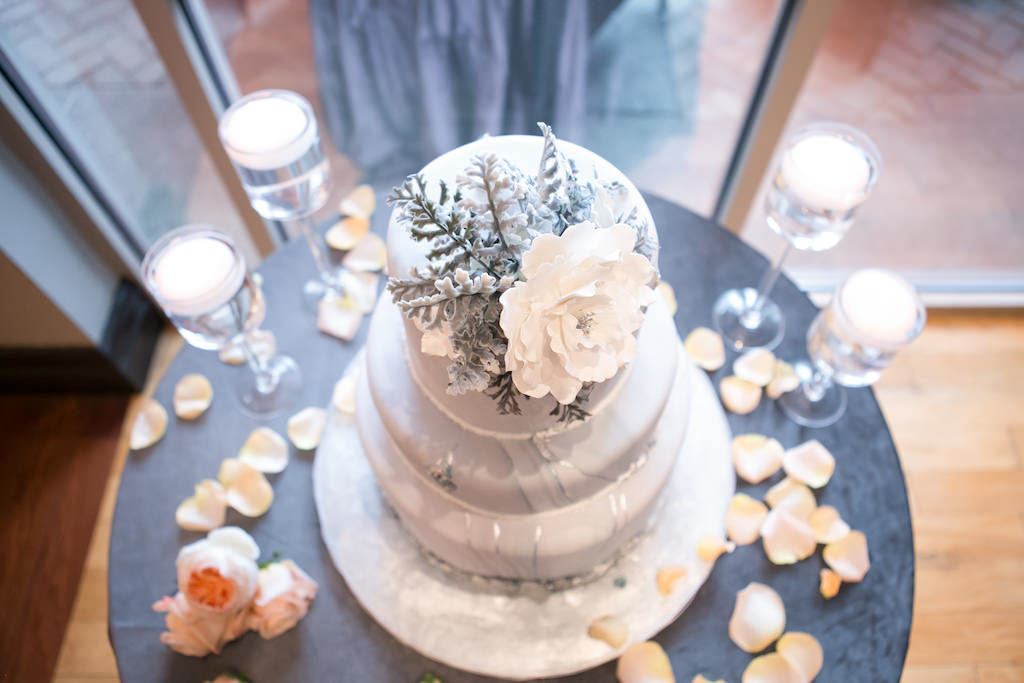 Three Tier Marble Wedding Cake with Silver Accents and White Sugar Flower Cake Topper on Round Table with Dusty Blue Tablecloth | Tampa Bay Photographer Carrie Wildes Photography | Linen Rental Gabro Event Services | Wedding Cake Alessi Bakeries