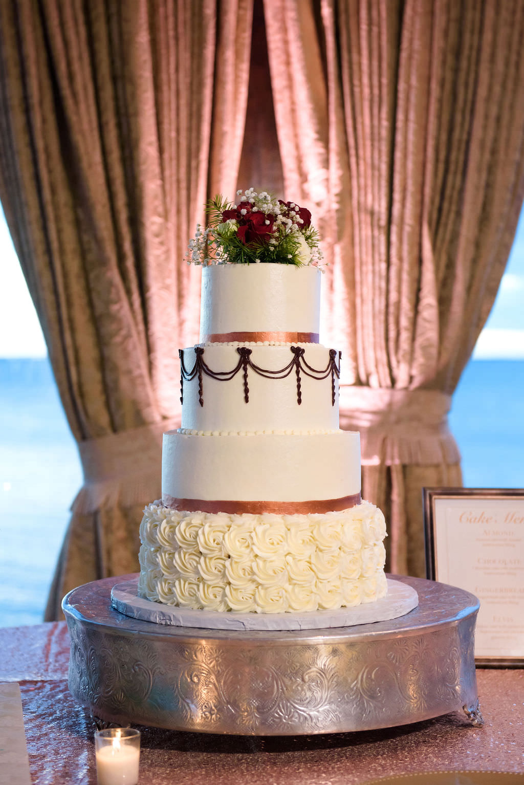 Four Tier White Wedding Cake with Rose Gold Accents and Real Flower Cake Topper on Silver Cake Stand