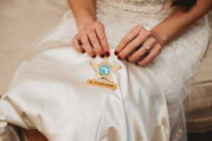 Tampa Bay Bridal Portrait Holding Spouse's Hillsborough Country Sheriff Department Law Enforcement Badge on Wedding Dress