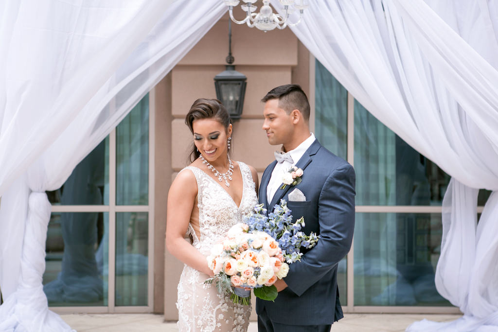 Florida Bride and Groom First Look Wedding Portrait, Bride in Lace and Illusion V Neckline and Tank Top Straps Wedding Dress with White, Blush Pink and Dusty Blue Floral Bouquet, Groom in Navy Blue Tuxedo | Tampa Bay Photographer Carrie Wildes Photography | Florist and Draping Gabro Event Services | Wedding Attire Nikki's Glitz and Glam Boutique | Hair and Makeup Destiny and Light Hair and Makeup Group | Hotel Wedding Venue Renaissance Tampa International Plaza