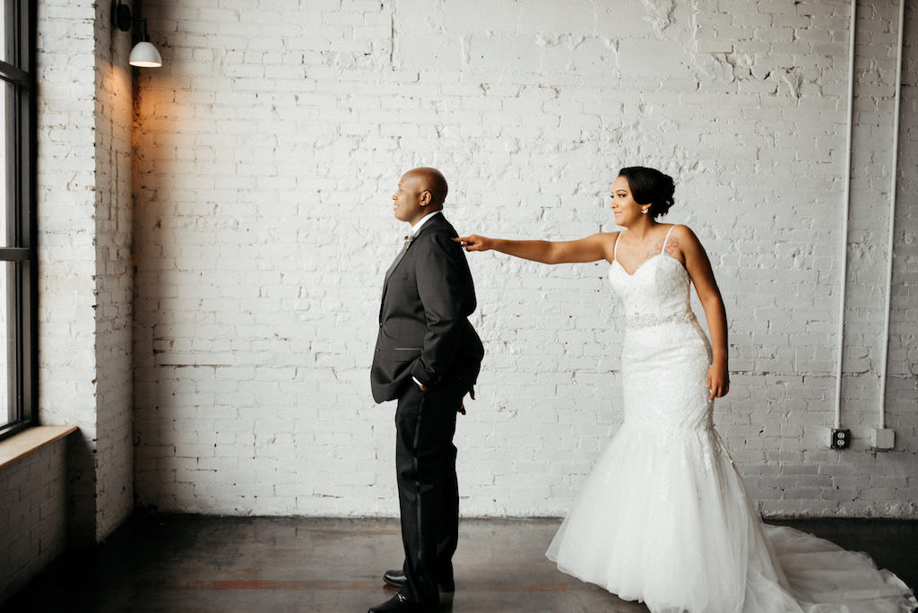 Tampa Bay Bride and Groom First Look Wedding Portrait, Bride in Spaghetti Strap, Sweetheart Neckline Lace Fitted Mermaid Style Wedding Dress with Tulle Skirt and Rhinestone Crystal Belt | Lakeland Industrial Modern Wedding Venue and Event Space Haus 820