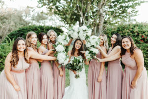 Florida Garden Bride and Bridesmaids Wedding Portrait, Bride in White Fit and Flare Wedding Dress, Bridesmaids in Mix and Match Long Mauve Dresses, Carrying White Floral Bouquet with Baby's Breath and Greenery | Tampa Bay Florist Monarch Events and Design