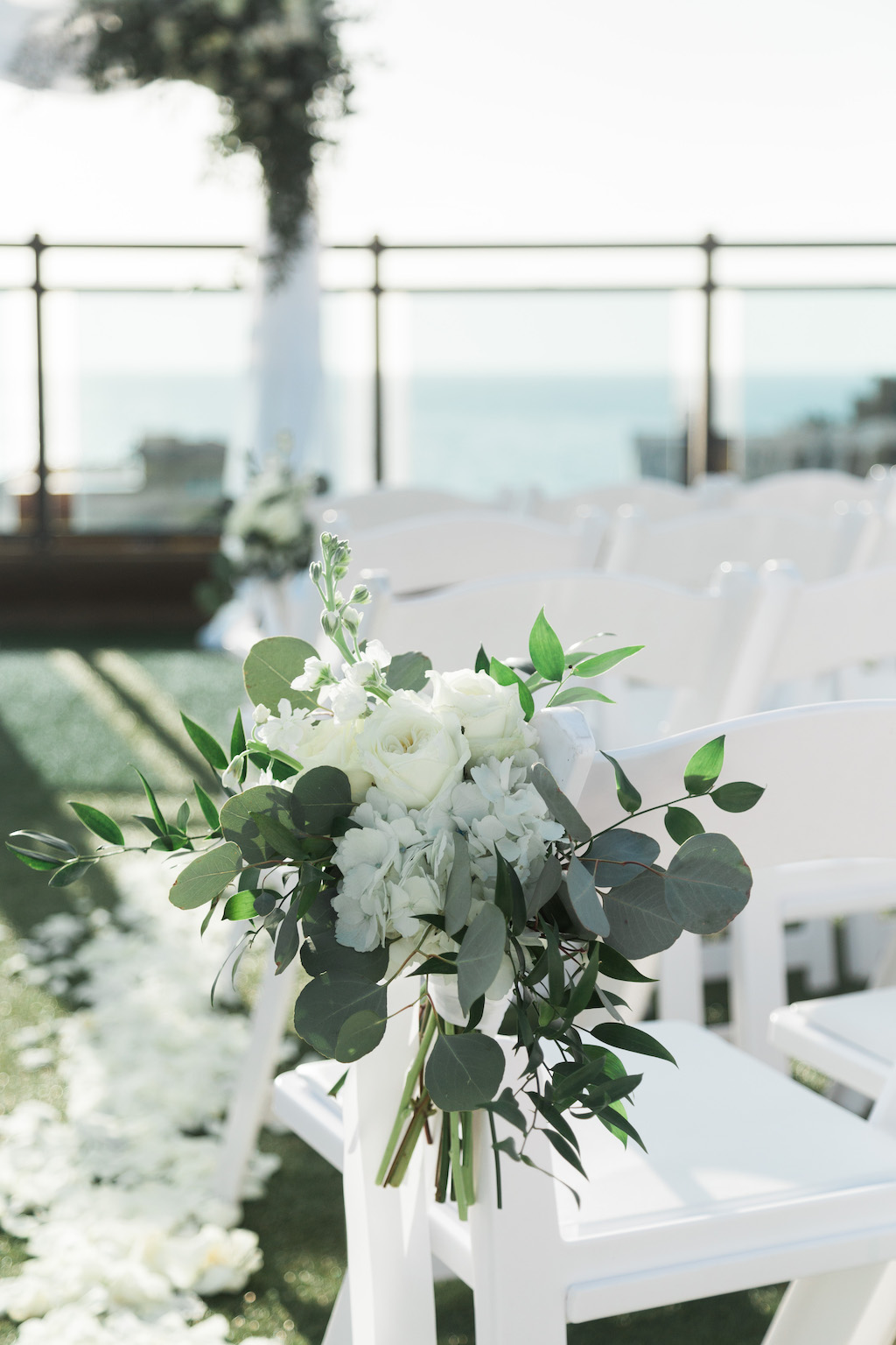 Rustic Beach Inspired Wedding Ceremony Decor, White, Ivory, Greenery and Eucalyptus Floral Arrangement on White Folding Chair