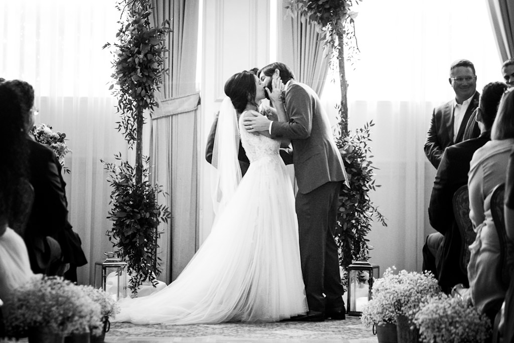 Florida Bride and Groom Exchange First Kiss in Black and White Wedding Portrait During Elegant South Tampa Wedding