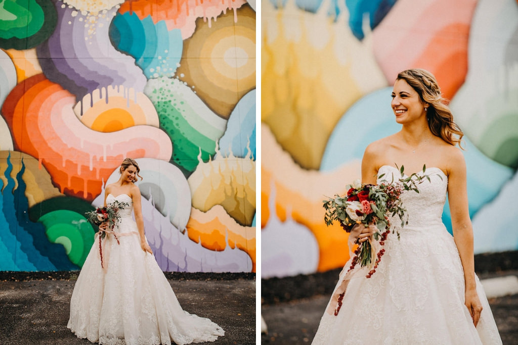 Tampa Bridal Portrait in front of Colorful Mural Art Graffiti Wall, Bride Wearing David’s Bridal White Strapless Sweetheart Neckline Ballgown Style Wedding Dress, Carrying Romantic Red Blush Pink and White Rose Wedding Bouquet with Greenery at Tampa Bay Wedding | Downtown St. Pete