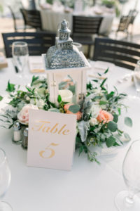 Rustic Elegant Wedding Reception Decor, White Lantern with Greenery and Floral Wreath Centerpiece and White and Gold Table Number Sign | Wedding Planner Gulf Beach Weddings
