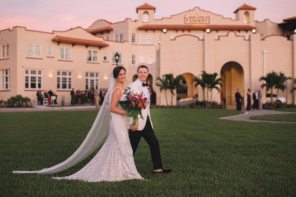 Tampa Bay Bride and Groom Wedding Portrait Outside Boutique Dunedin Hotel Wedding Venue Fenway Hotel, Bride in Sleeveless White Sequin Sheath Wedding Dress with Long Tulle Veil, Carrying Tropical Inspired Wedding Bouquet with Colorful Florals and Greenery