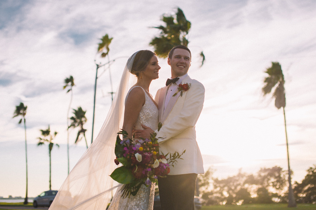 Florida Bride and Groom Wedding Portrait During Golden Hour, Bride in Sleeveless White Sequin Sheath Wedding Dress with Long Tulle Veil, Carrying Tropical Inspired Wedding Bouquet with Colorful Florals and Greenery | Tampa Bay Boutique Hotel Wedding Venue Fenway Hotel