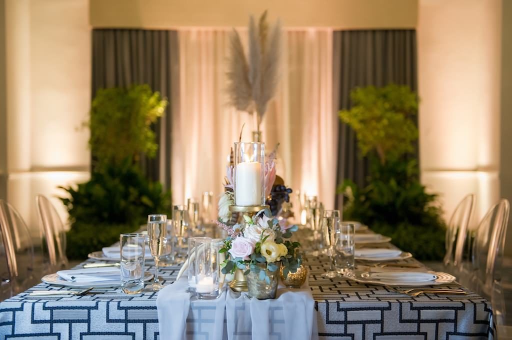 Bohemian Chic Inspired Wedding Decor, Long Rectangle Reception Tables with Blue Geometric Linen and White Sheer Runner, Neutral Tones Low Floral Centerpieces with White Ivory and Pink Roses, King Protea, Thistle, Lisianthus, Antlers, Feathers, Scabiosa, Mercury Glass Votive Candle Holder, Crystal Champagne Flutes, Pampas Grass in Large Clear Glass Jar, Against Hotel Ballroom Backdrop with Greenery and Chandelier Lighting | Tampa Bay Wedding Photographer Andi Diamond Photography | St. Pete Beach Wedding Venue The Don Cesar | Tampa Bay Wedding Planner UNIQUE Weddings + Events | Linen Rentals Over the Top Linens | Rentals A Chair Affair