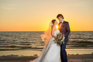 Florida Bride and Groom Wedding Portrait at Sunset on St. Pete Beach, Bride in Soft White A-line Wedding Dress With Sheer Top, Tulle Veil with Floral Hair Accessorie, Carrying Bohemian Inspired Floral Wedding Bouquet | St. Petersburg Beach Resort and Hotel Wedding Venue The Don Cesar | Tampa Bay Wedding Photographer Andi Diamond Photography | Tampa Wedding Dress Shop Truly Forever Bridal