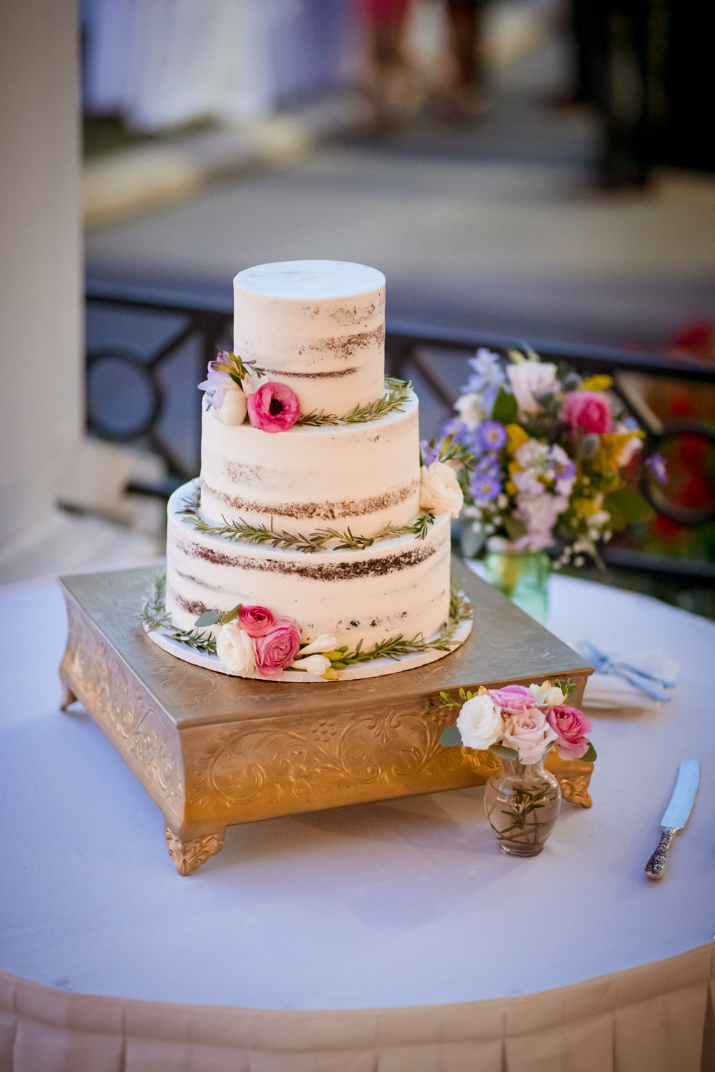 Elegant Southern Chic Three Tier Naked Wedding Cake with White Forsting, Pink and White Flowers and Greenery, on Gold Square Cake Stand, with Colorful Floral Arrangement on Florida Wedding Cake Table