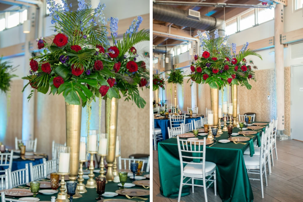Eclectic Jewel Toned Themed Reception Wedding Decor at Downtown Reception Venue Tampa River Center, Large Gold Vase Centerpieces with Overflowing Green Blue Purple Mix Flower and Red Rose Floral Arrangements | Emerald Green Tablecloth, Vintage Multi-colored Glass Goblets, Gold Flatware, Tall Silver Candelabras | Tampa Bay Wedding Photographer Andi Diamond Photography