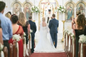 Tampa Bay Bride and Groom During Greek Orthodox Wedding Ceremony with White Rose and Greenery Wedding Decor