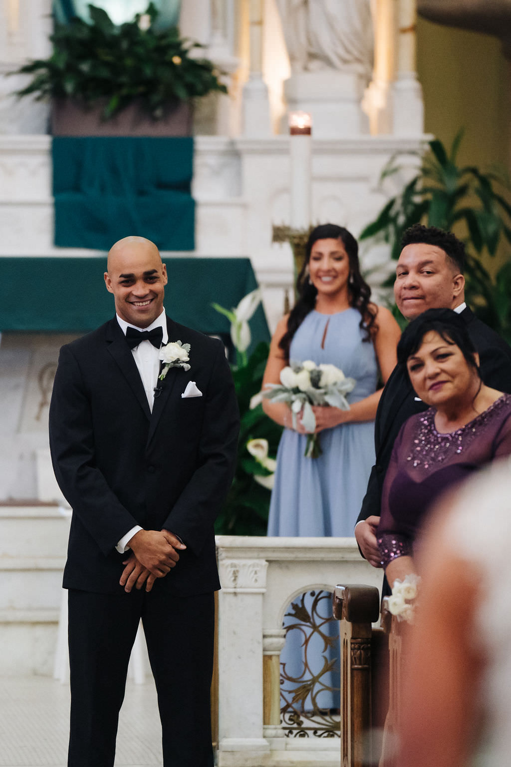 Groom in Classic Black Tuxedo and Bowtie During Wedding Processional at Sacred Heart Catholic Church Tampa | Photographer Grind & Press Photography