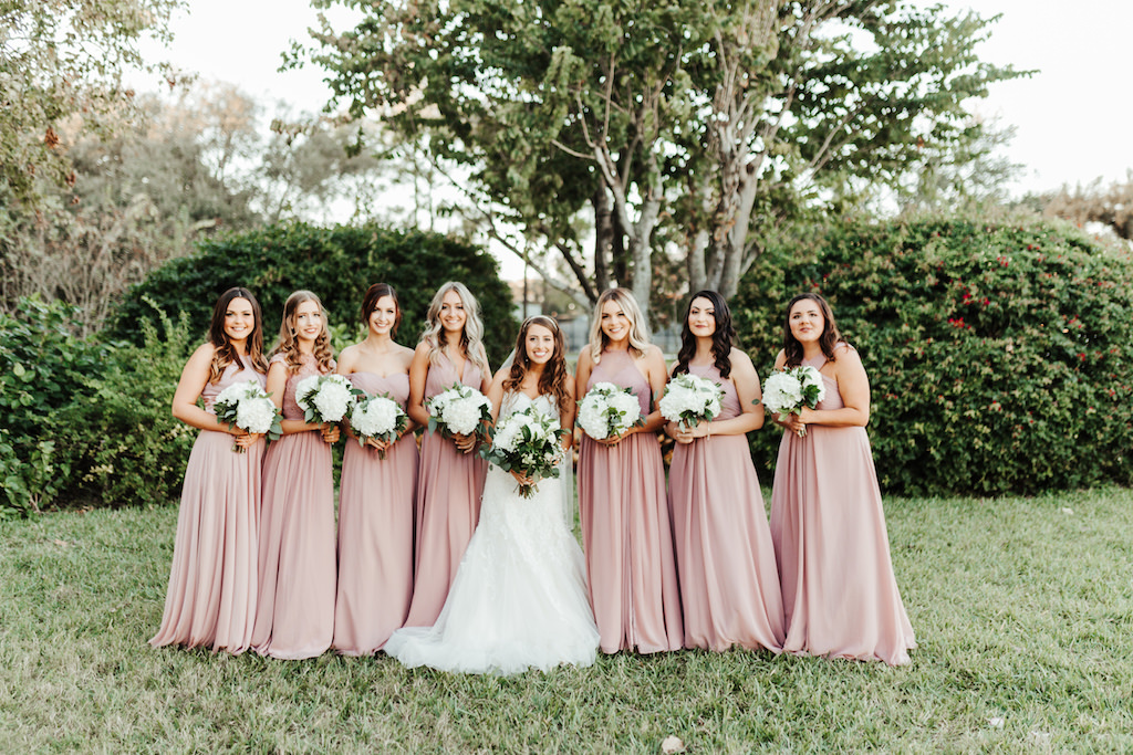 Florida Garden Bride and Bridesmaids Wedding Portrait, Bride in White Fit and Flare Wedding Dress, Bridesmaids in Mix and Match Long Mauve Dresses, Carrying White Floral Bouquet with Baby's Breath and Greenery | Tampa Florist Monarch Events and Design