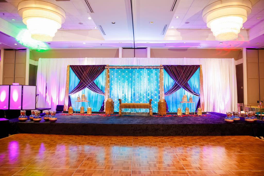 Elegant Colorful Traditional Indian Tampa Wedding | White, Blue and Purple Linen Backdrop with Purple Uplighting, Gold Furniture Accents | Hotel Ballroom Wedding Venue Hilton Tampa Airport Westshore