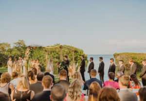 Destination FloridaWaterfront Ceremony Photo, Bride and Groom under Bamboo Arch with Tropical Wedding Decor, With Colorful Flowers, Pink Ginger, King Proteas, Orchids, with Palm Leaf Greenery and Pampas Grass | Sarasota Wedding Venue Longboat Key Club