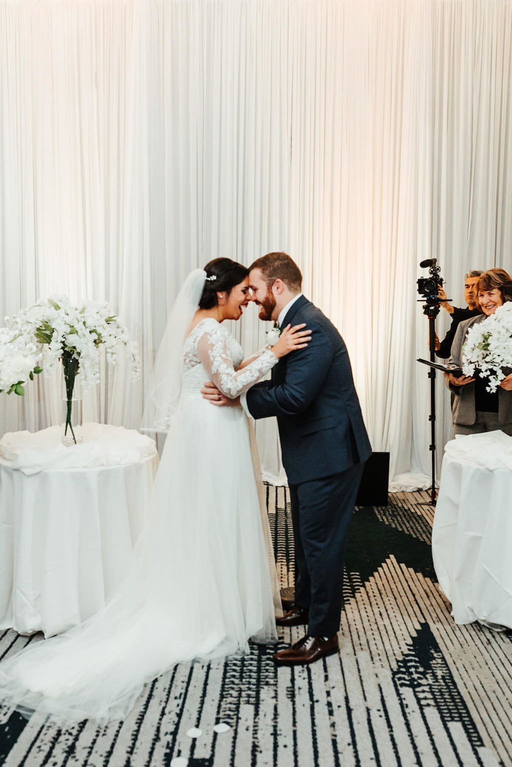 Tampa Bride and Groom Embrace During Wedding Ceremony Portrait, White Floral Decor and Draping | Florida Boutique Hotel and Wedding Venue The Hotel Alba in Westshore | Gabro Event Services