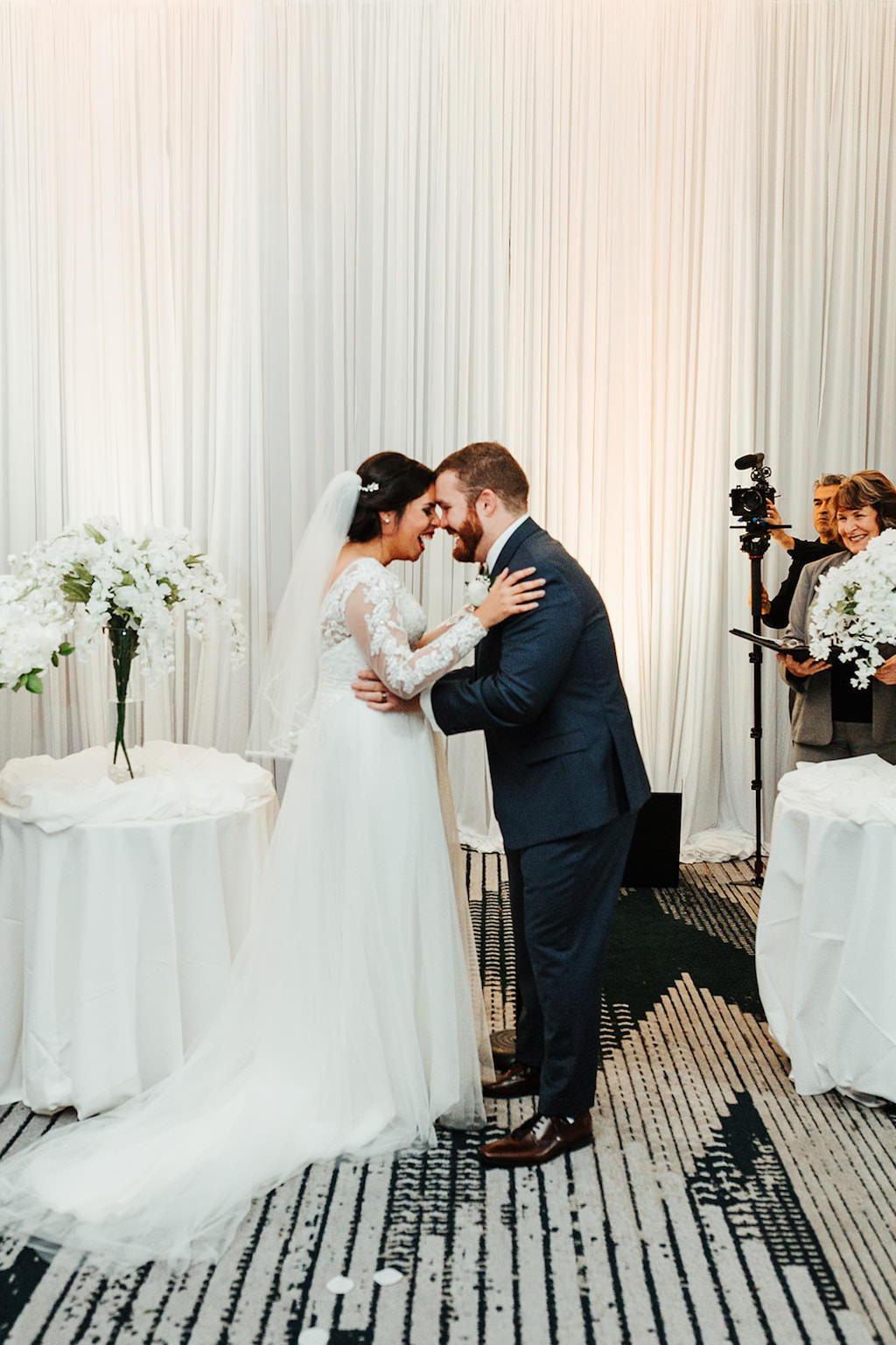Tampa Bride and Groom Embrace During Wedding Ceremony, White Floral Decor and Draping | Florida Boutique Hotel and Wedding Venue The Hotel Alba in Westshore | Gabro Event Services