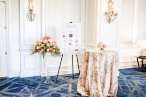 Sponsor Sign, Tropical Bouquet with Pink King Protea, Peach, White and Orange Florals with Greenery Chic Garden Inspired Wedding Decor, Pink Floral Table Linens, Ballroom of The Ritz Carlton Sarasota | Tampa Bay Wedding Photographer Lifelong Photography Studios | Over the Top Rental Linens | Custom Stationery A&P Designs