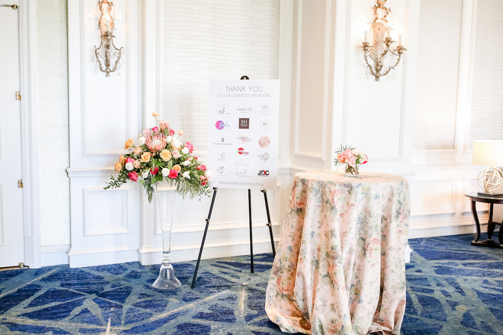 Sponsor Sign, Tropical Bouquet with Pink King Protea, Peach, White and Orange Florals with Greenery Chic Garden Inspired Wedding Decor, Pink Floral Table Linens, Ballroom of The Ritz Carlton Sarasota | Tampa Bay Wedding Photographer Lifelong Photography Studios | Over the Top Rental Linens | Custom Stationery A&P Designs
