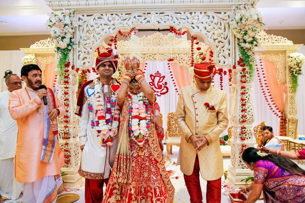 Indian Wedding Ceremony Portrait, Bride and Groom Traditional Rituals, Bride in Red and Gold Sari with Red, White and Blush Pink Floral Lei, White Canopy with White, Blush Pink Floral Arrangements