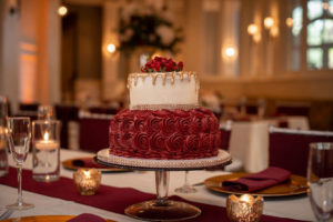 FSU Inspired Two Tier Wedding Cake, With Burgundy Floral Detailing, Smooth White Icing with Gold Drip and Rhinestone Embellishment, Red Rose Topper