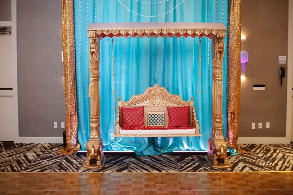 Elegant Traditional Indian Wedding Decor, Gold Arch and Gold Swing Chair with Red Cushions and Blue Satin Backdrop | Hotel Ballroom Wedding Venue Hilton Tampa Airport Westshore