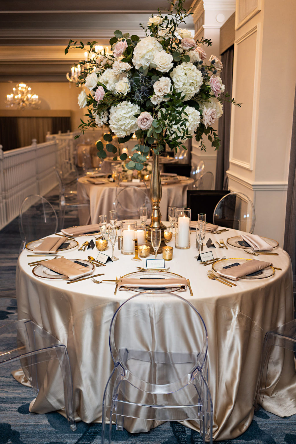 Romantic Garden Inspired Tall Floral Centerpiece with White Hydrangeas, Blush Pink Roses, Thistle and Greenery, Blush Pink Table Linens, Ghost Clear Acrylic Chairs | Historic St. Pete Beach Hotel The Don Cesar | Over The Top Rentals | Tampa Bay Florist Bruce Wayne Florals | Florida Wedding Planner Parties A La Carte | A Chair Affair |