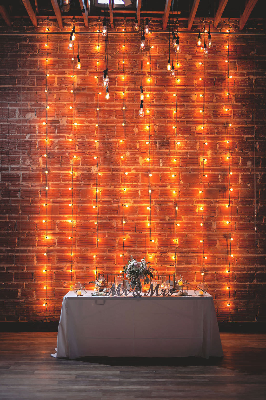 Romantic Sweetheart Table at Wedding Reception with Exposed Brick Wall and String Lighting | Industrial Tampa Bay Wedding Venue NOVA 535