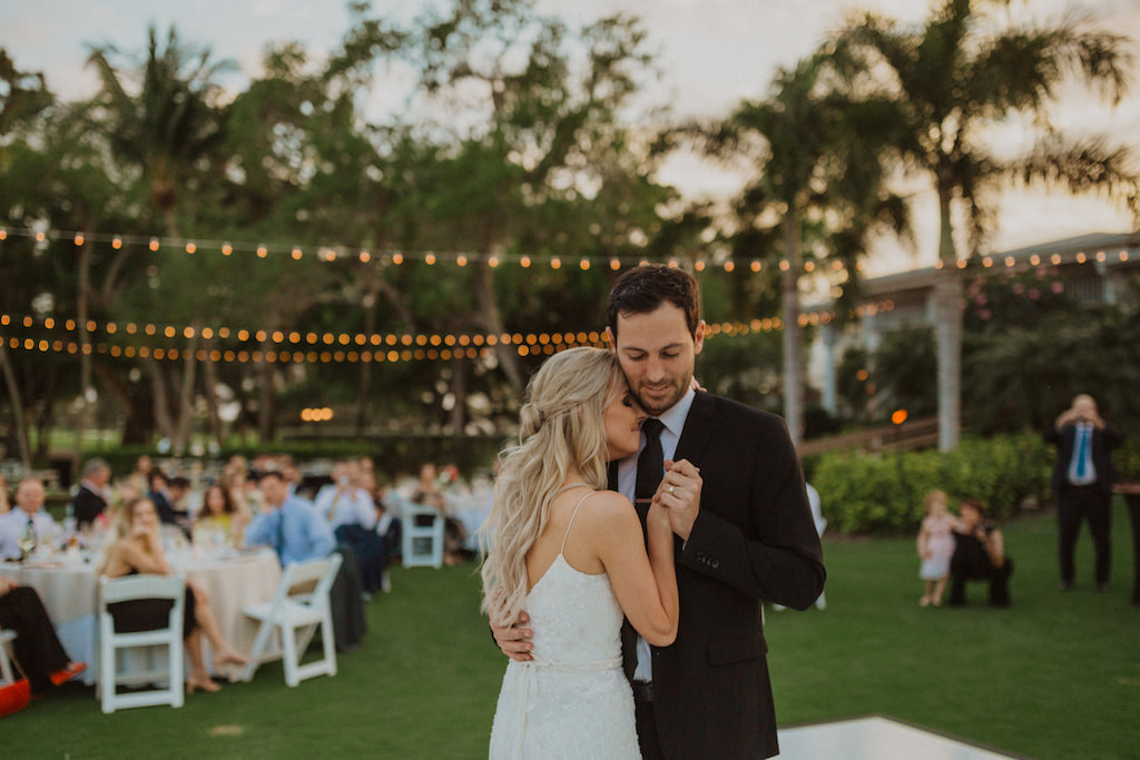Boho Inspired Bride and Groom During First Dance, at Outdoor Reception on Lawn, with String Lighting and Palm Trees | Sarasota Wedding Venue Longboat Key Club