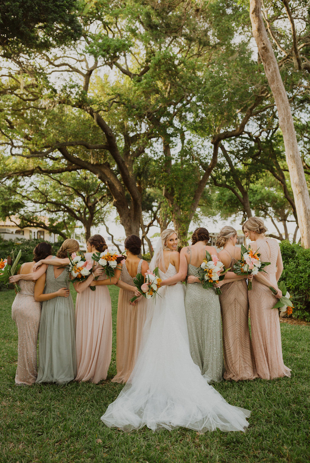 Florida Bride and Bridesmaids Wedding Portrait, Bride in Spaghetti Strap White Beaded Karen Willis Holmes Wedding Dress, Bridesmaids in Pastel Beige Sage and Blush Mix and Match Beaded Adrianna Papell Dresses, Carrying Tropical Wedding Bouquet with Colorful Flowers, Pink Ginger, Orchids, with Greenery in Longboat Key