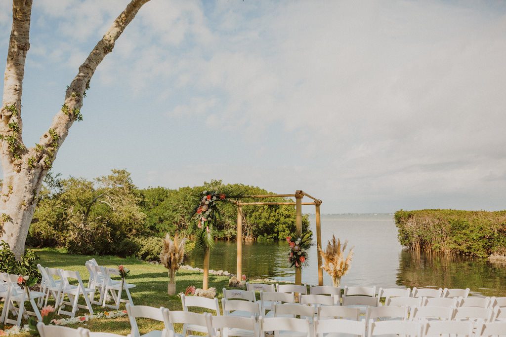 Tropical Destination Florida Outdoor Waterfront Wedding Ceremony with Bamboo Wedding Arch, Wedding Decor with Colorful Flowers, Pink Ginger, King Proteas, Orchids, with Greenery and Pampas Grass | Sarasota Wedding Venue Longboat Key Club