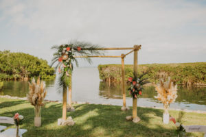 Tropical Destination Florida Outdoor Waterfront Wedding Ceremony with Bamboo Wedding Arch, Wedding Decor with Colorful Flowers, Pink Ginger, King Proteas, Orchids, with Greenery and Pampas Grass | Sarasota Wedding Venue Longboat Key Club