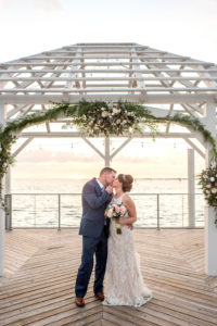 Florida Bride and Groom Kiss Portrait, Just Married After Waterfront Dockside Wedding Ceremony Under Cabana, Nautical Inspired Decor, White, Ivory, Blush Pink, and Green Floral Arch | | Tampa Bay Hotel and Wedding Venue The Godfrey Hotel & Cabanas